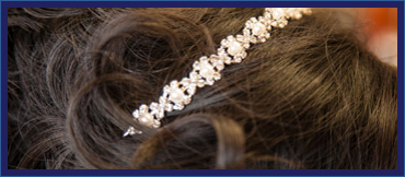 close up image of a bridal hair updo, featuring diamond and pearl headband